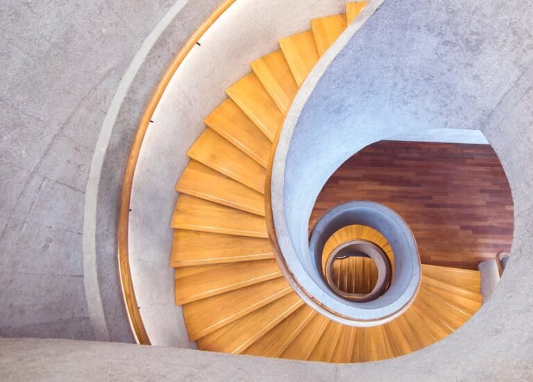 Aerial view of a stylish spiral staircase with wooden steps and a concrete interior.