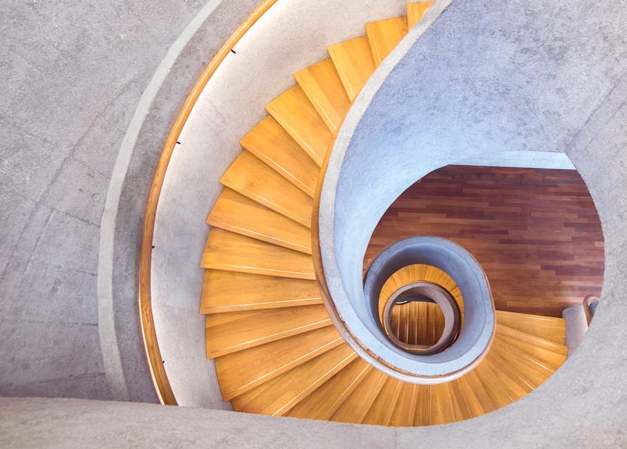 Aerial view of a stylish spiral staircase with wooden steps and a concrete interior.