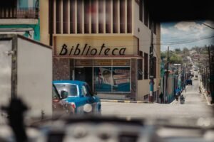 A bustling street in Matanzas, Cuba, showcasing a library facade and urban life.